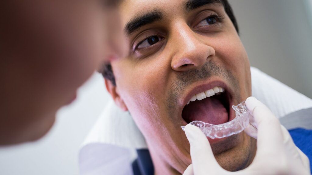 Paciente en consulta dental prob&aacute;ndose un alineador transparente de ortodoncia invisible durante una revisi&oacute;n